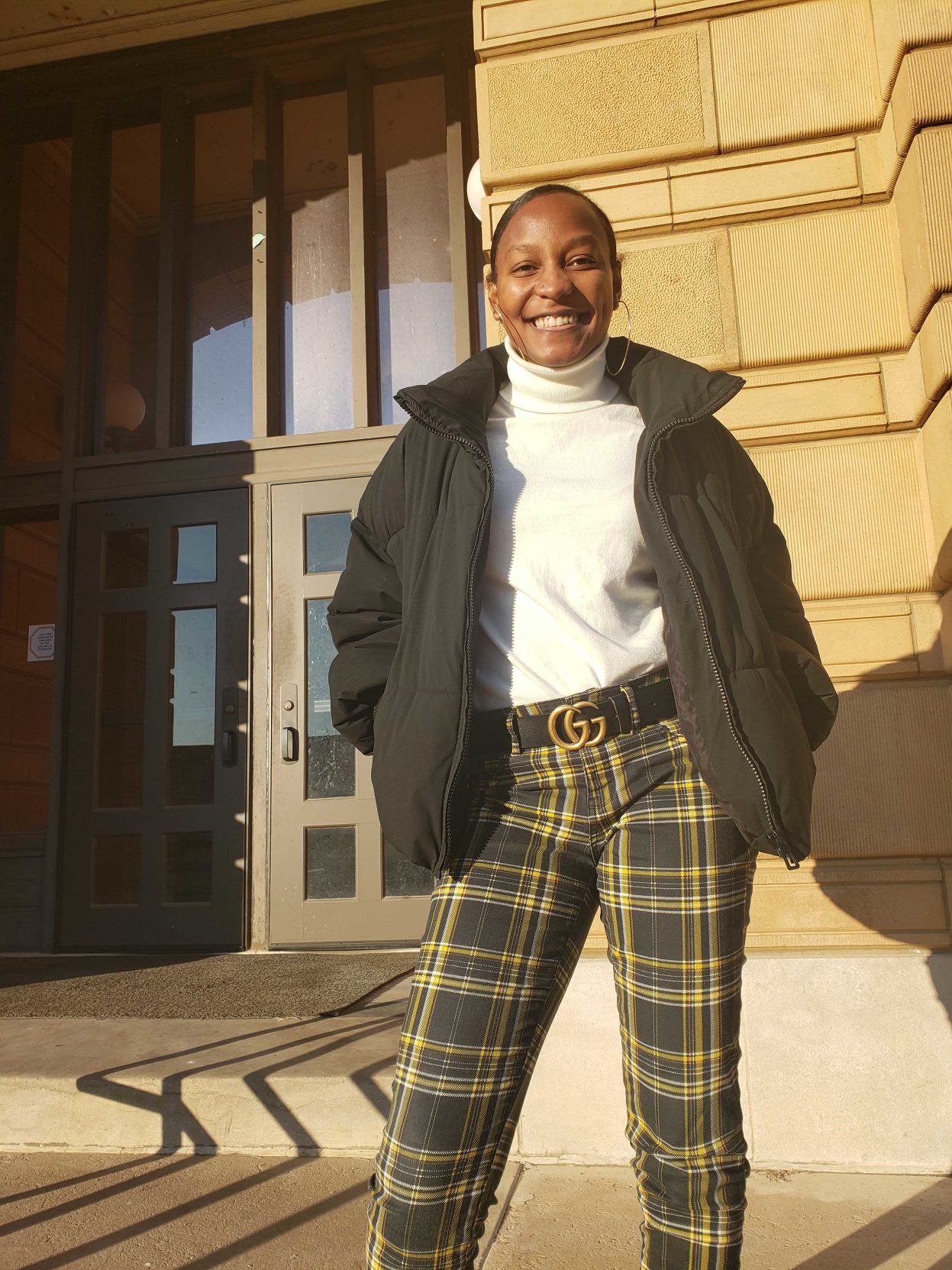 Woman stands in front of the building and smiles at the camera